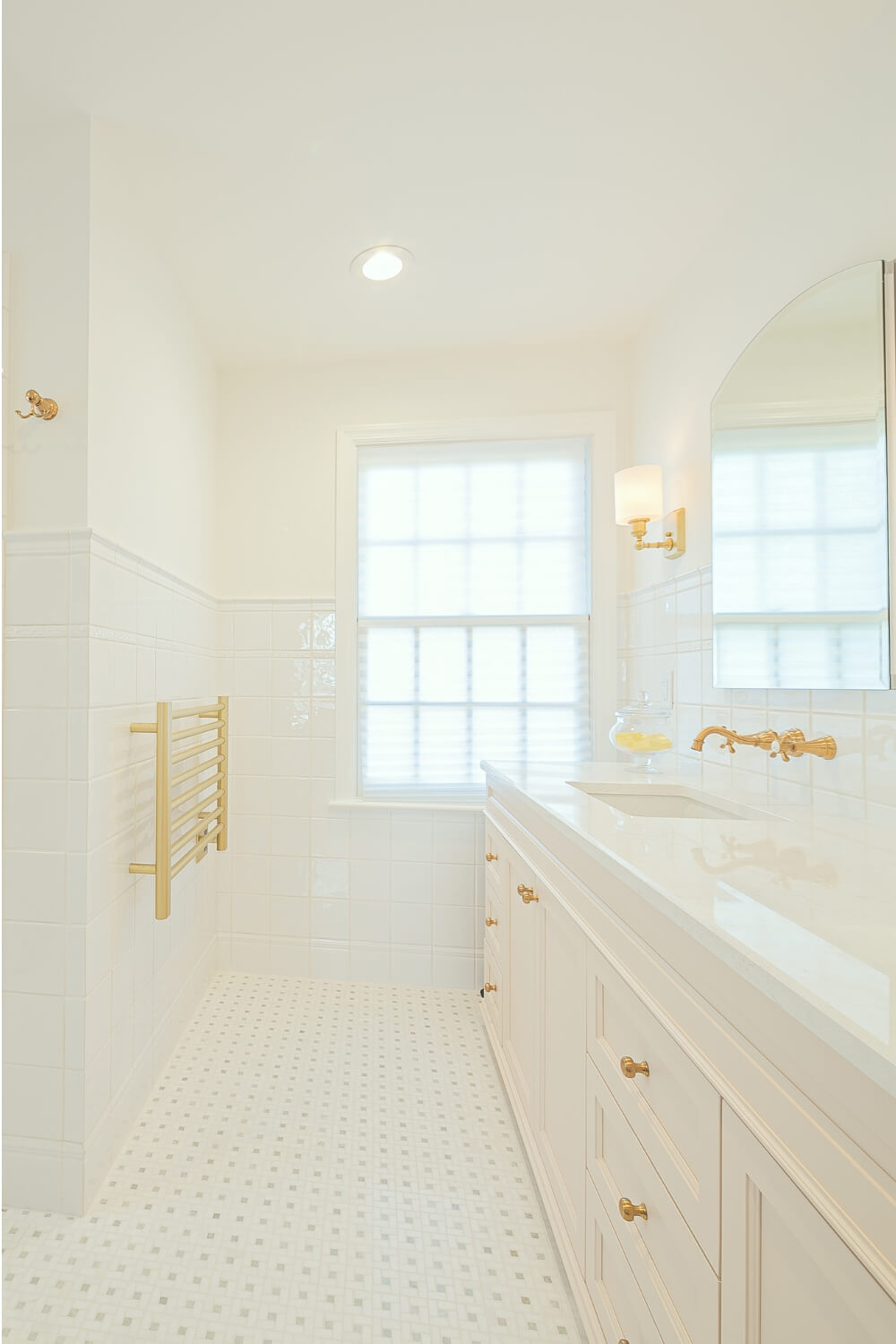 elegant-bathroom-renovation-with-towel-rack-and-gold-details Bathroom with a gold towel warmer and white subway tiles